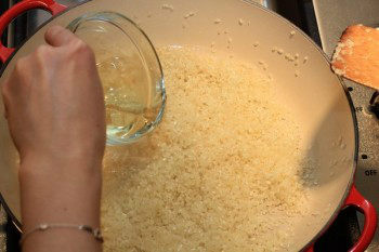 white wine added to rice and garlic in a cast iron pan