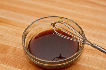 sauce inside a bowl next to a small whisk on cutting board
