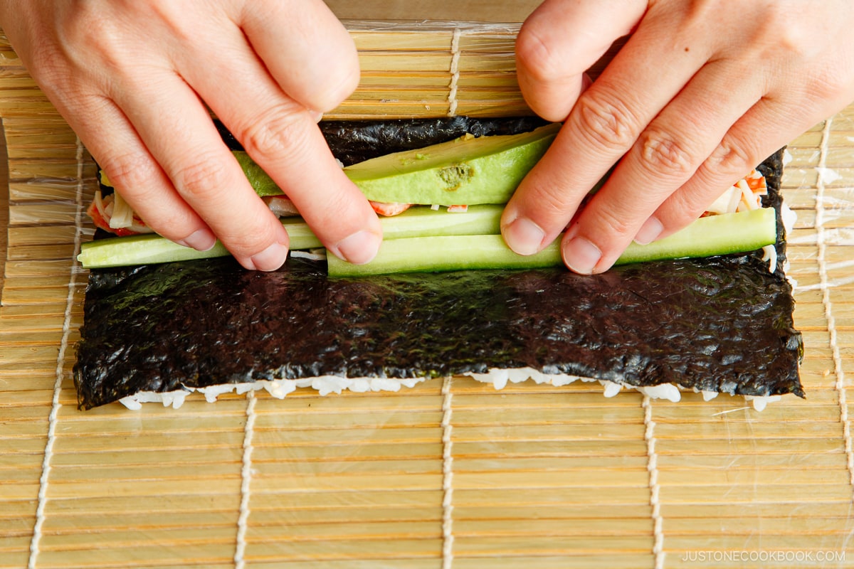 Carefully roll the nori and rice over the filling.
