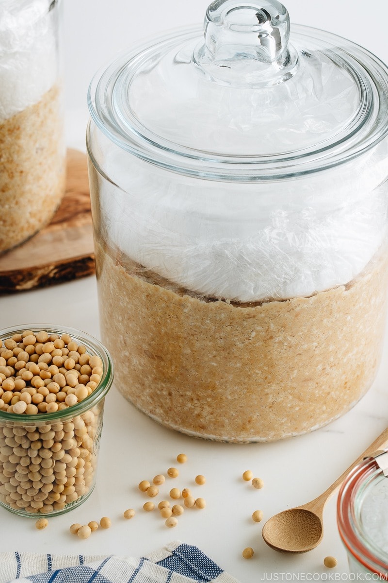 Homemade miso is in the making; soybeans, salt, and koji mixture in a glass jar.