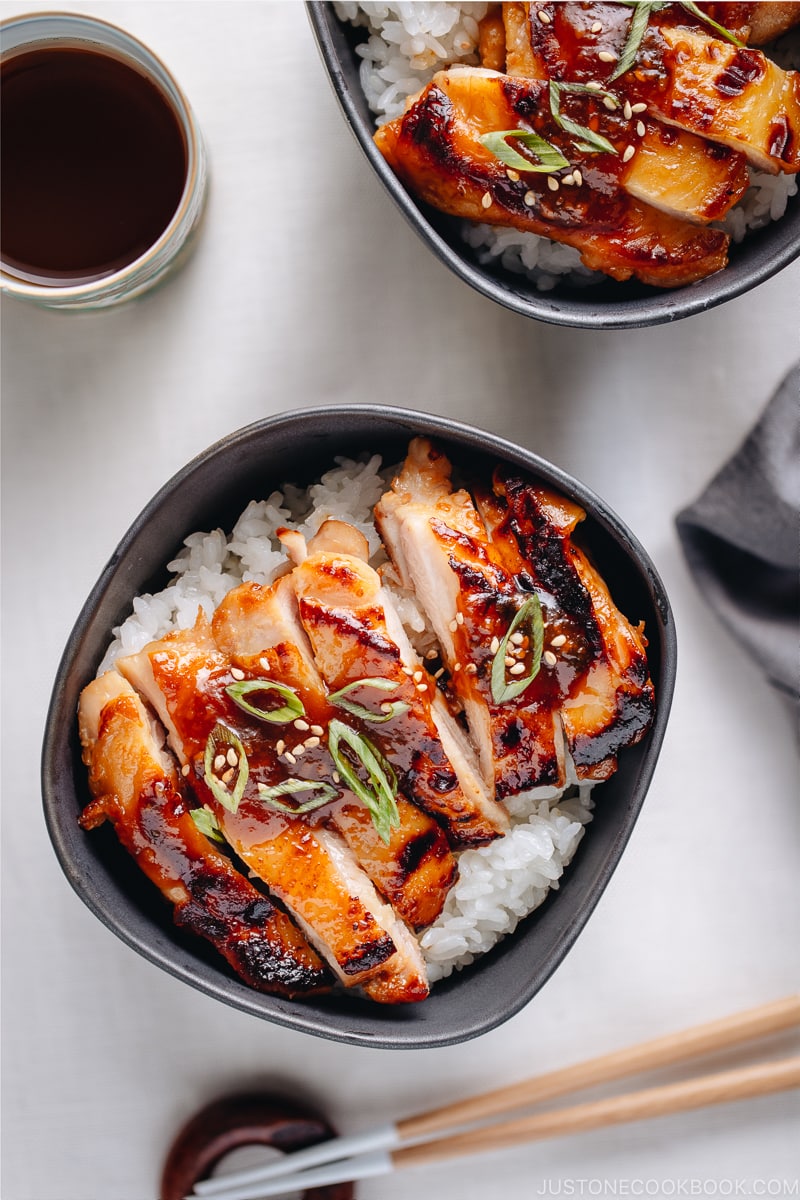 Miso chicken over steamed rice, garnished with sesame seeds and green onion.