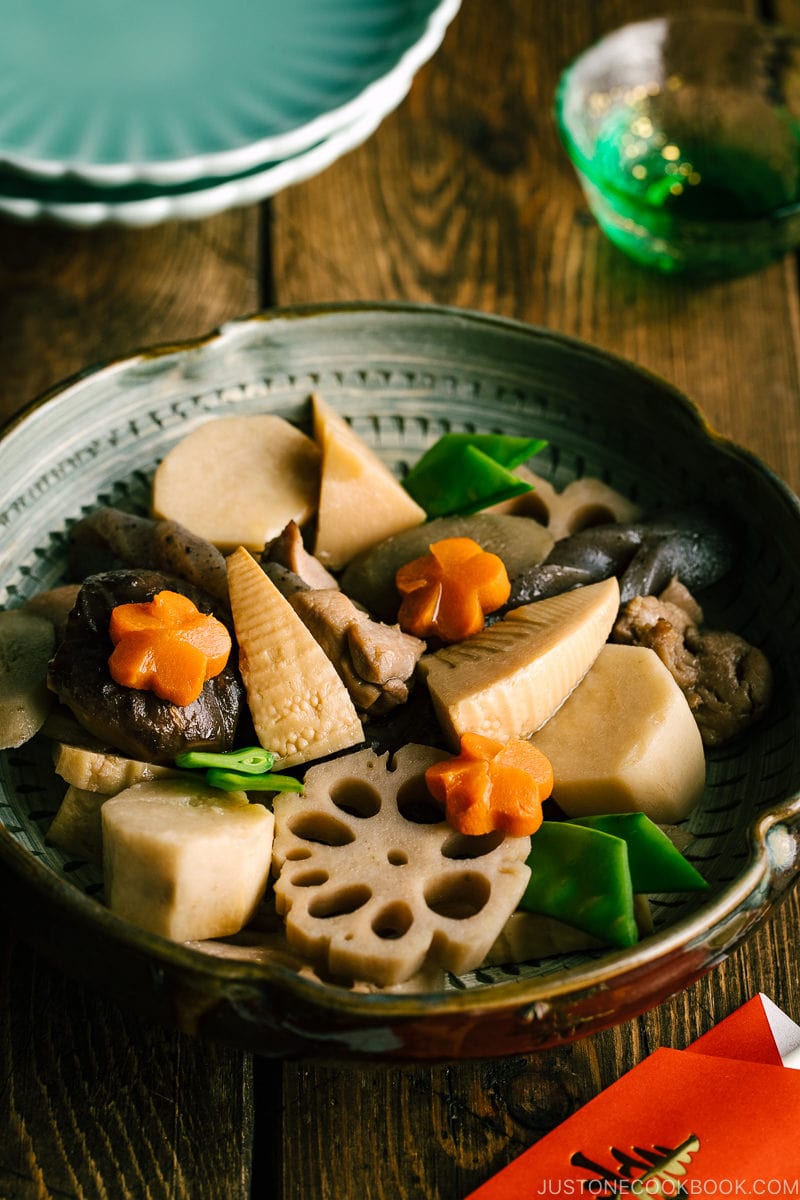 A Japanese ceramic bowl containing simmered chicken and vegetables.