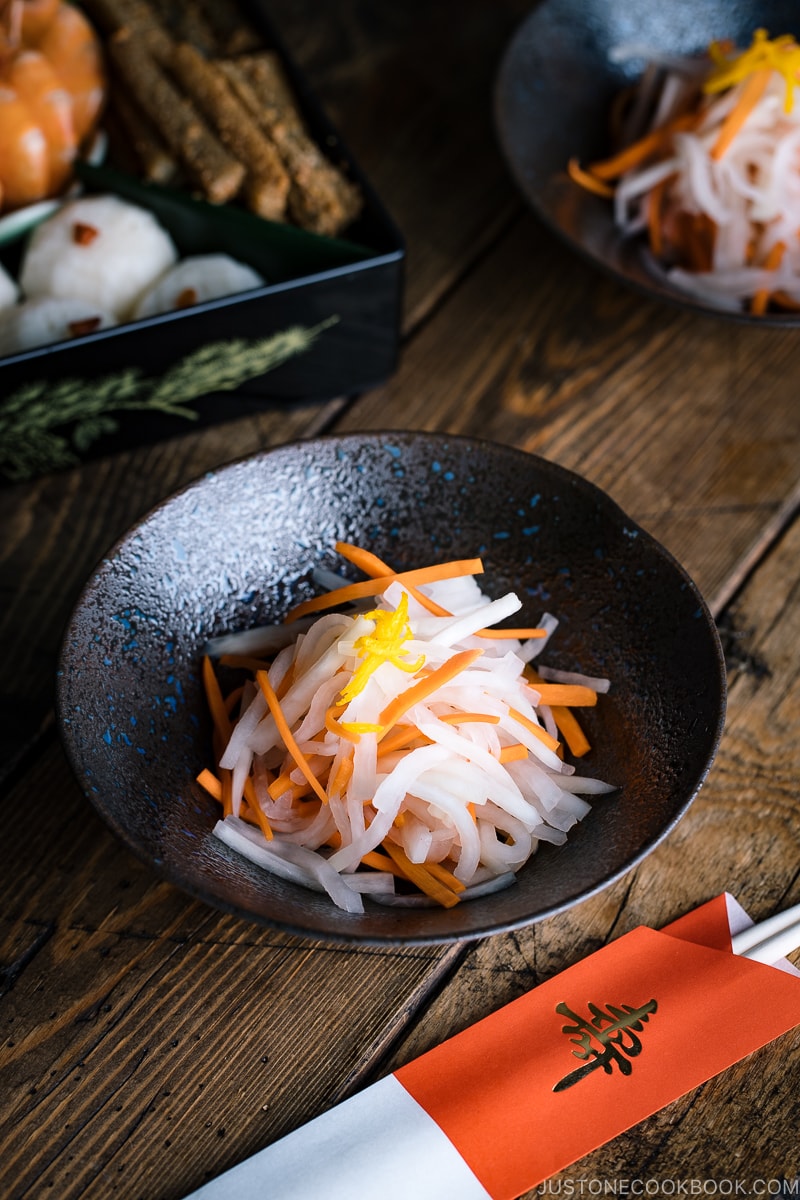 A black bowl containing Namasu (Japanese Daikon and Carrot Salad).