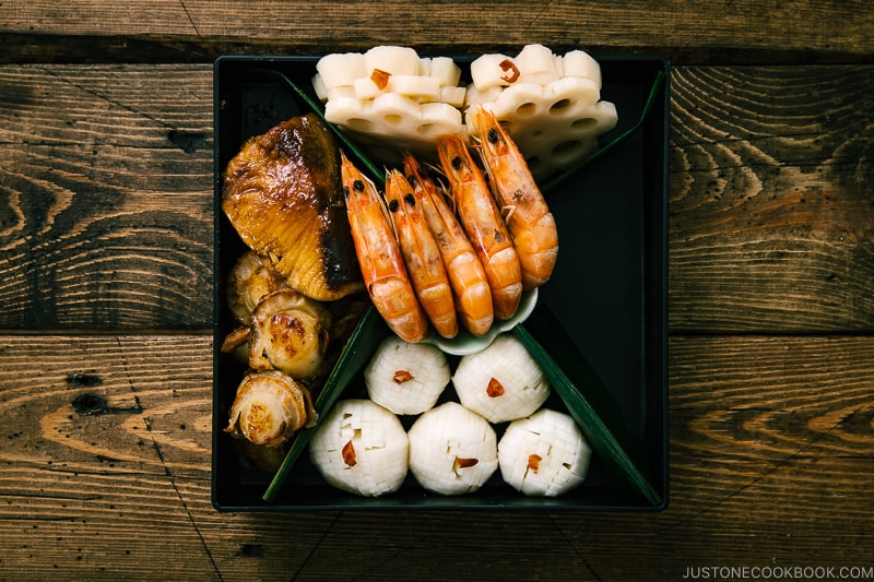 Shirmp, scallop, fish, pickles, and lotus root in the osechi box.