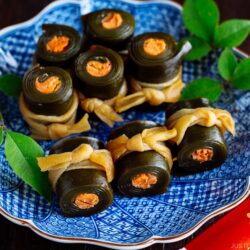 A blue Japanese plate containing salmon kombu rolls.
