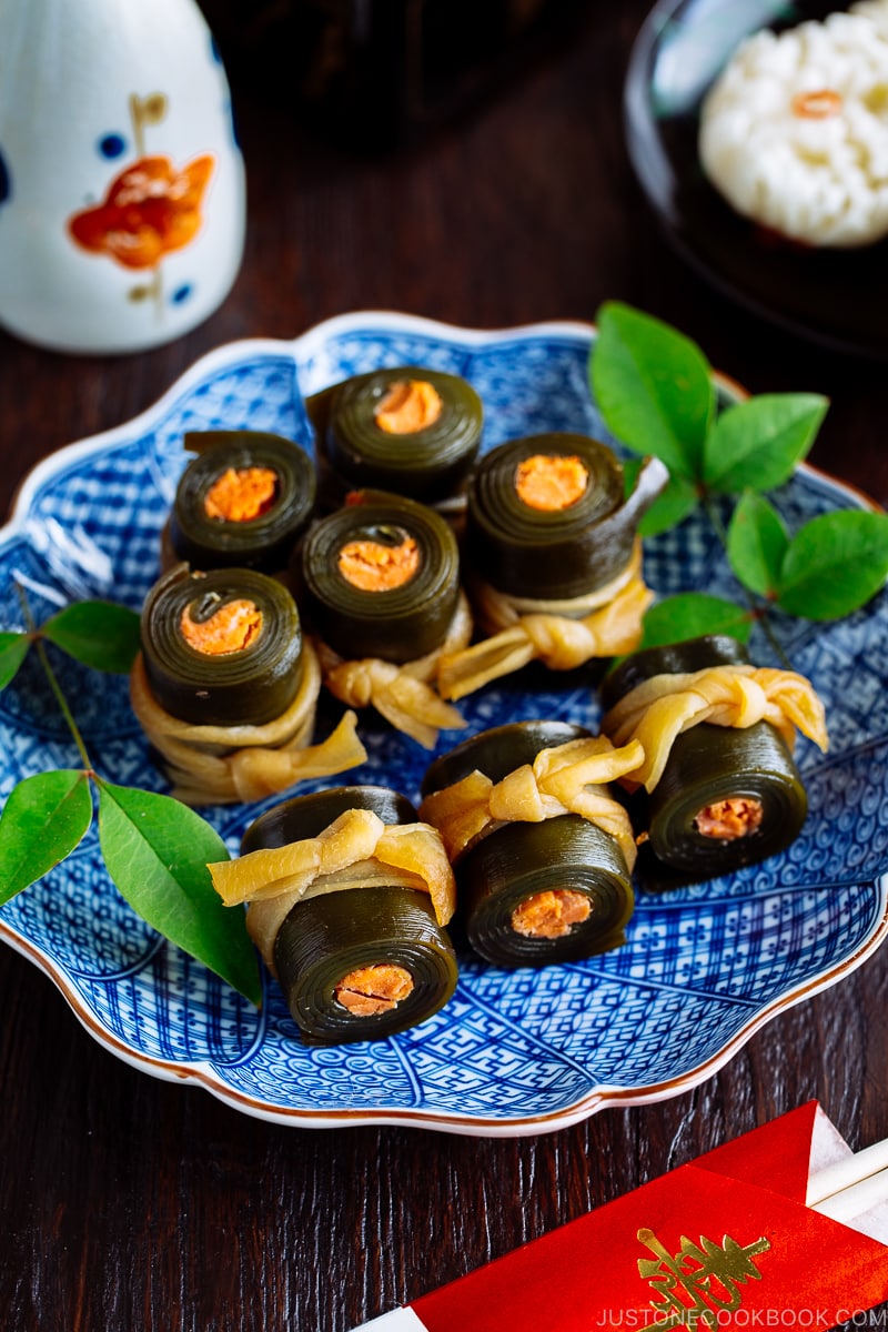 A blue Japanese plate containing salmon kombu rolls.