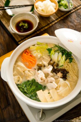 A donabe containing vegetables and pork in a savory miso soy milk broth.