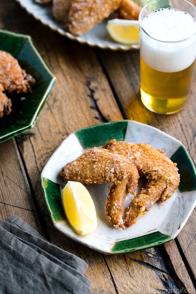 Crispy fried chicken wings on a Japanese plate along with a glass of cold beer.