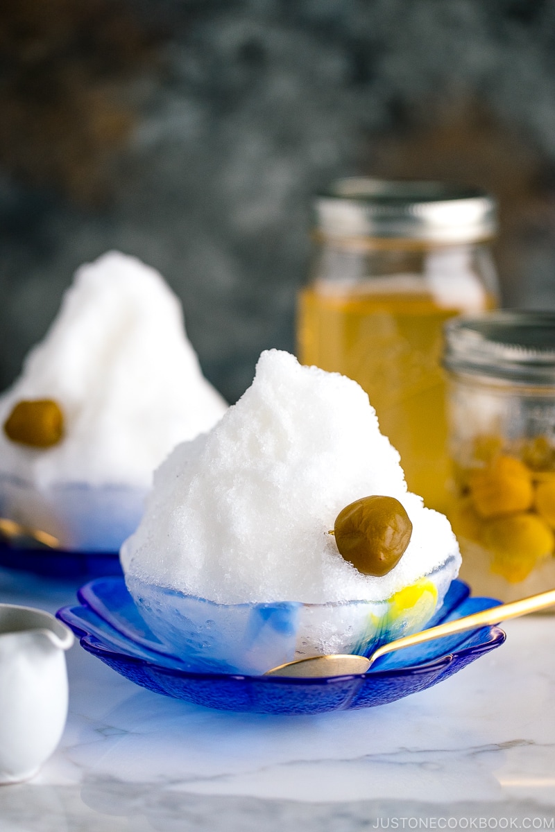 A blue glass bowl containing shaved ice, ume plum syrup, and ume compote.