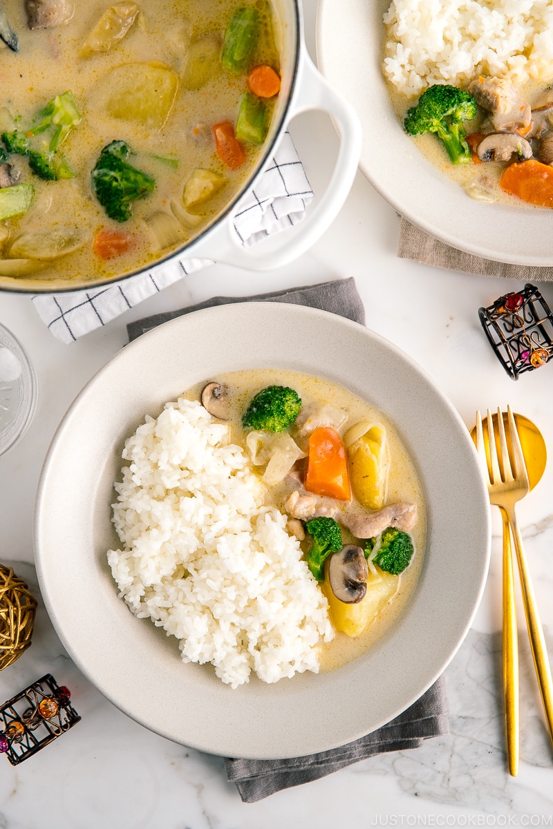 A beige ceramic dish containing steamed rice and Japanese cream stew.