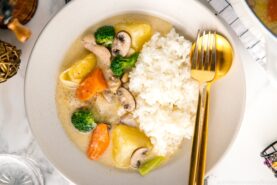 A beige ceramic dish containing steamed rice and Japanese cream stew.