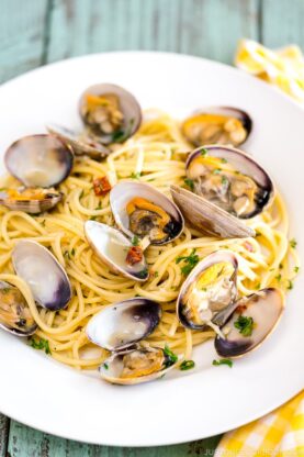A white plate containing clam pasta.