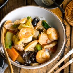 A white bowl containing Chukadon (Seafood and Vegetable Stir Fry Over Rice).
