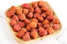 A bamboo strainer containing umeboshi (Japanese pickled plums).