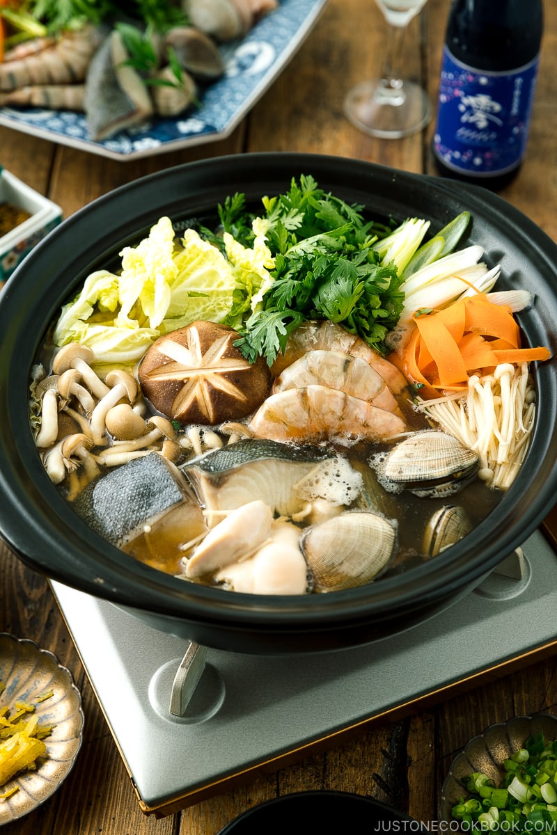 A donabe (earthenware hot pot) containing meat, seafood, and vegetables.