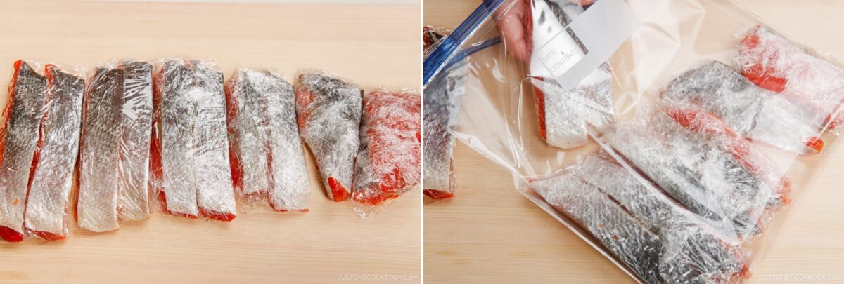 Individually plastic-wrapped fish fillets are laid out on a wooden surface; on the right, some fillets—prepared using how to cut salmon into Javanese style fillets—are being placed into a labeled resealable plastic bag for storage.