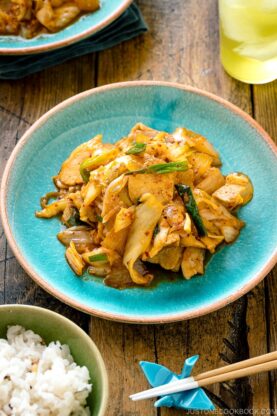 A Japanese ceramic plate containing Pork Kimchi Stir-Fry called Buta Kimchi. It's served with steamed rice.