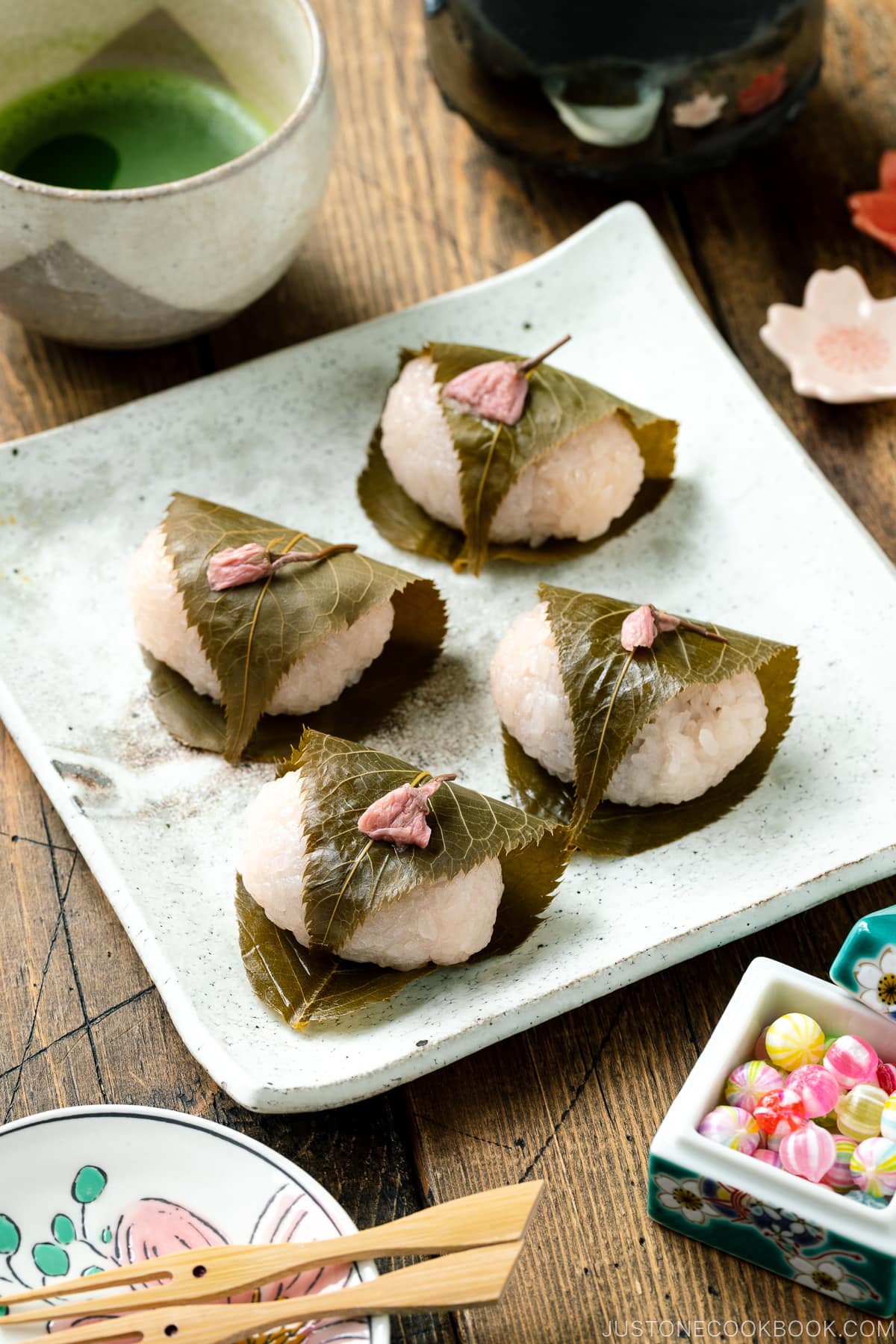 A white square plate containing sakura mochi.