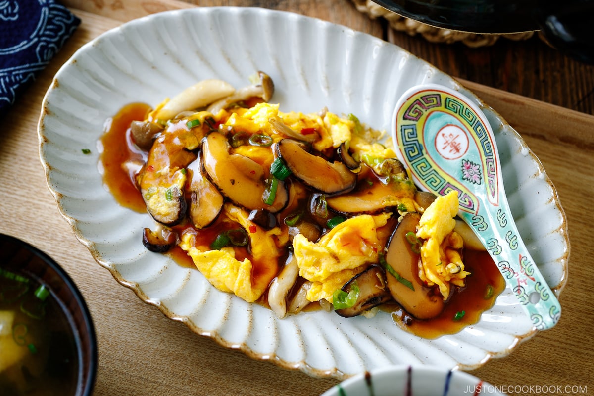 A fluted oval shape containing stir-fried mushrooms and eggs drizzled with ankake sauce.