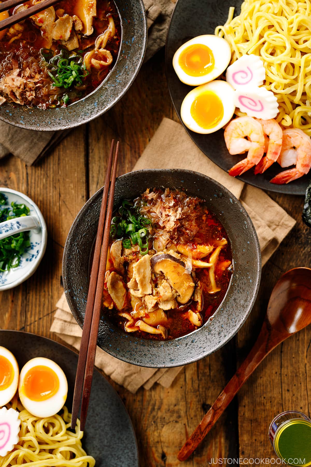 Bowls of Tsukemen dipping soup broth and a plate of ramen noodles and toppings.