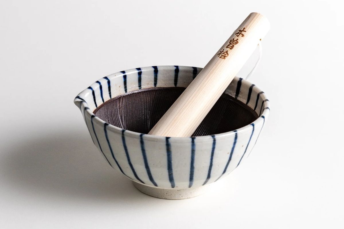 Traditional Japanese rice mortar and pestle in a ceramic bowl for authentic rice pounding and cooking preparation. Perfect for Japanese cuisine lovers and home cooks.