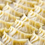 A baking sheet containing perfectly wrapped gyoza.