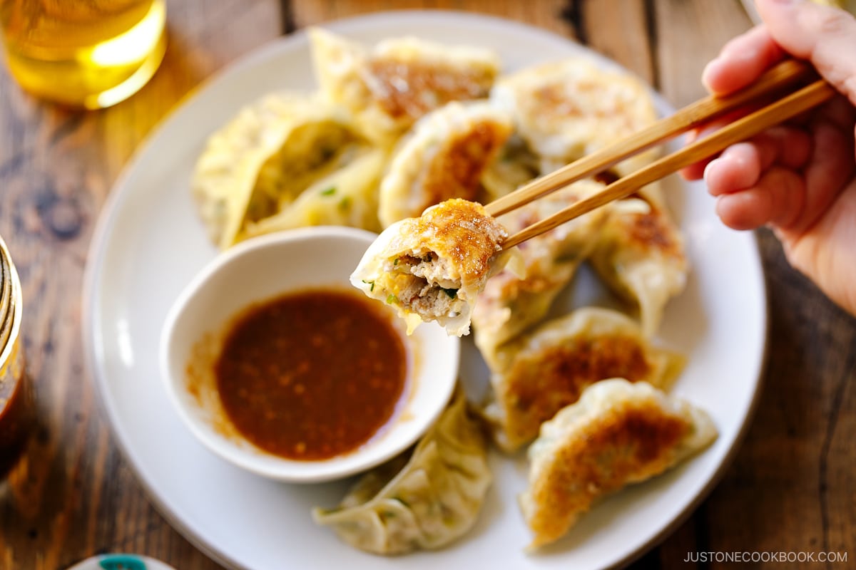 A round plate containing Japanese pan-fried dumplings, Napa Cabbage Gyoza, served with a savory miso dumpling sauce.