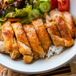 A bowl containing Chicken Teriyaki glazed with homemade teriyaki sauce on the bed of steamed rice.