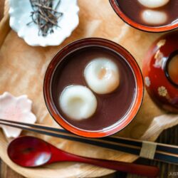 Red lacquered bowls containing red bean soup with mochi balls.