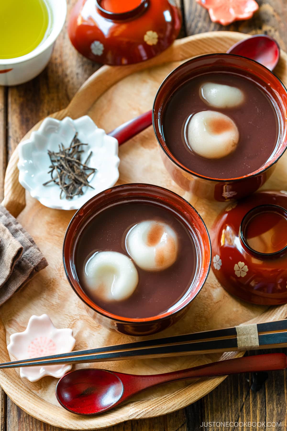 Red lacquered bowls containing red bean soup with mochi balls.