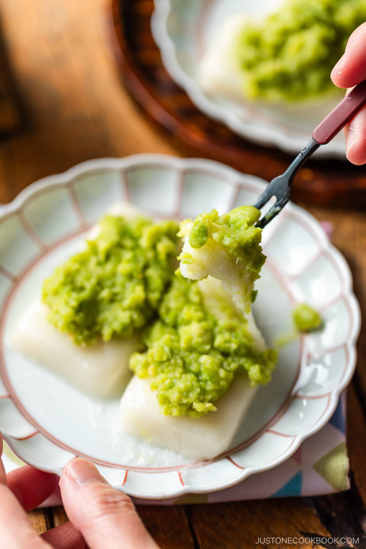 A fluted plate containing Zunda Mochi, topped with sweet edamame paste.