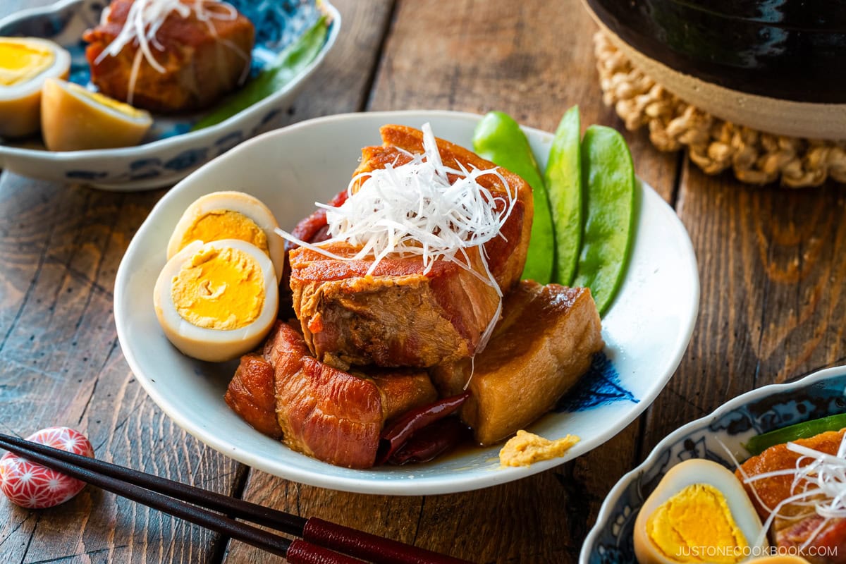 A bowl containing Kakuni, Japanese braised pork belly, served with julienned white scallion, boiled egg, and karashi mustard.