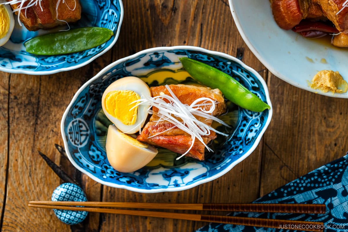 A bowl containing Kakuni, Japanese braised pork belly, served with julienned white scallion, boiled egg, and karashi mustard.