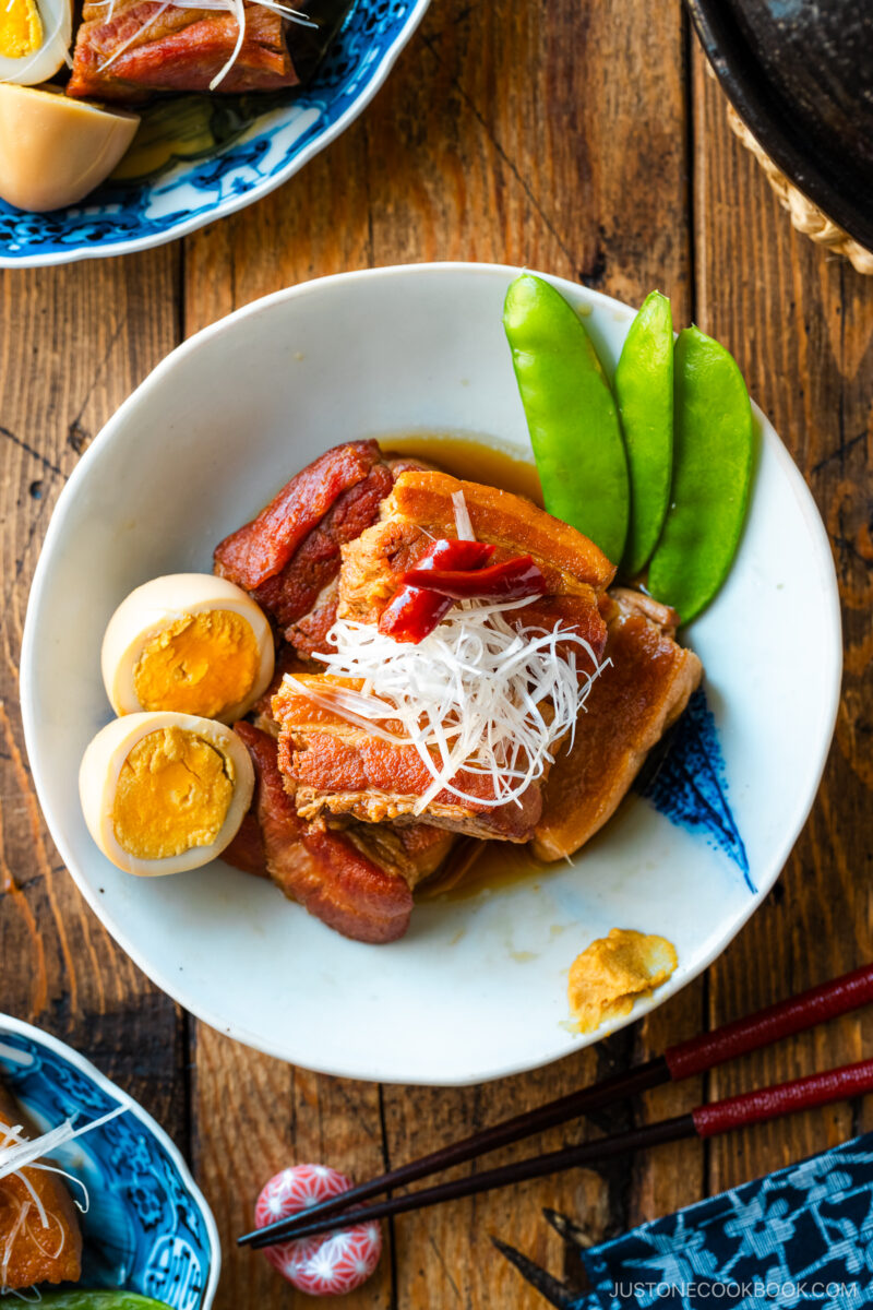 A bowl containing Kakuni, Japanese braised pork belly, served with julienned white scallion, boiled egg, and karashi mustard.