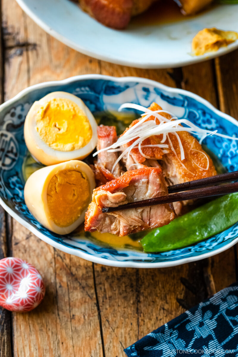 A bowl containing Kakuni, Japanese braised pork belly, served with julienned white scallion, boiled egg, and karashi mustard.