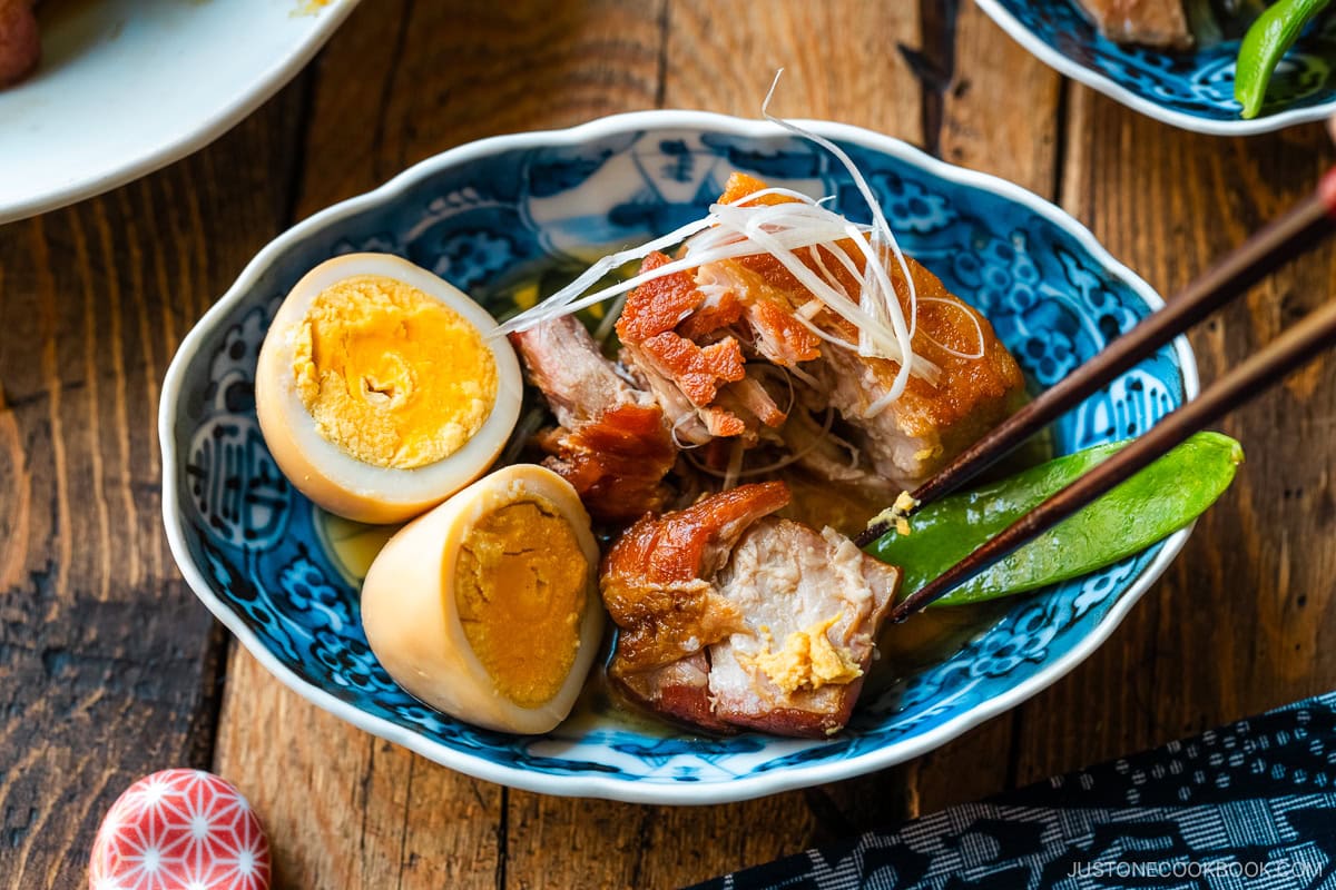 A bowl containing Kakuni, Japanese braised pork belly, served with julienned white scallion, boiled egg, and karashi mustard.