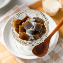 A glass bowl containing cubed Hojicha Jelly drizzled with sweetened condensed milk.