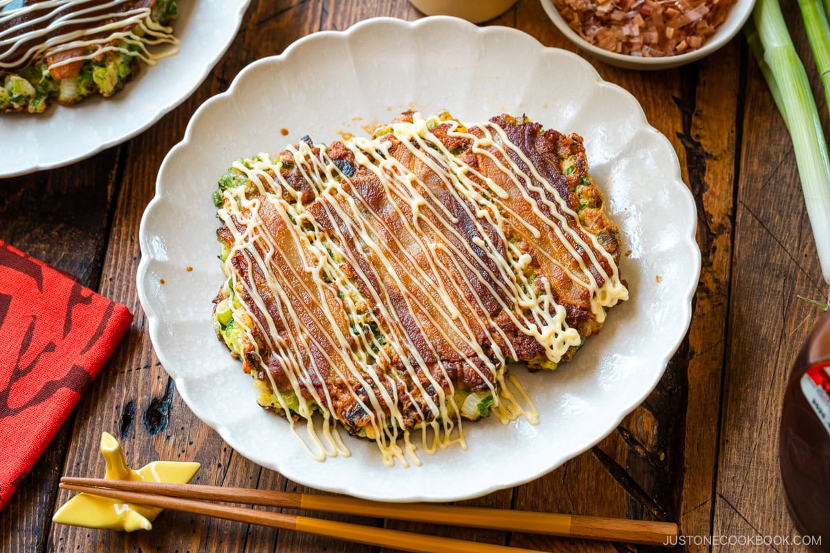 White scalloped plates containing negiyaki, a savory Japanese scallion pancake.