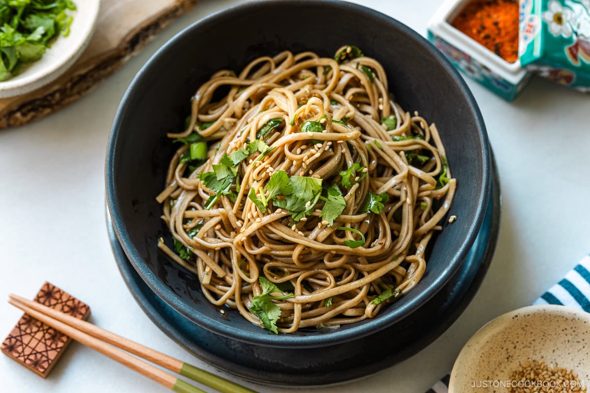 A black bowl containing Soba Noodle Salad topped with sesame seeds and chopped cilantro and green onions.