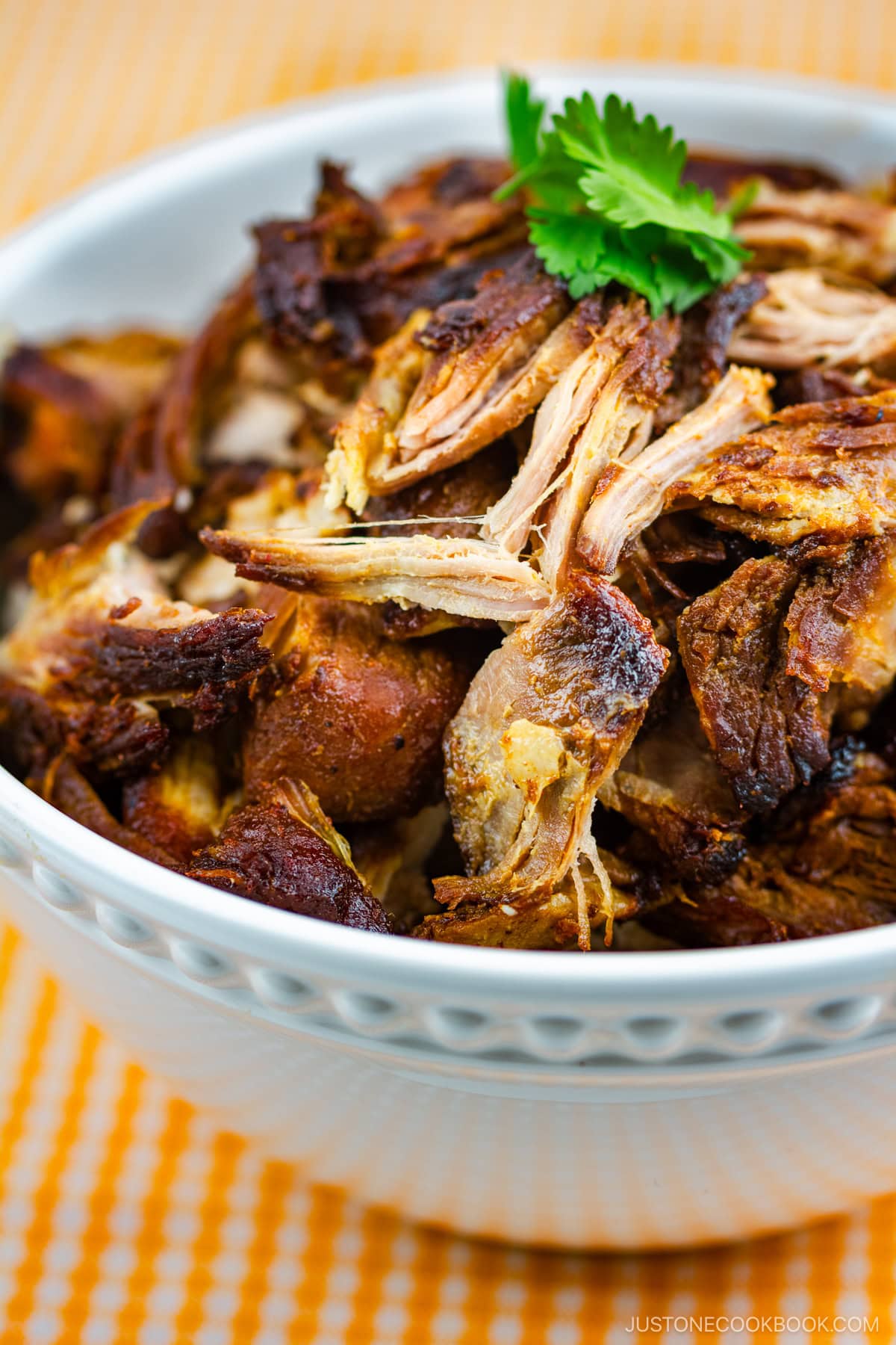 A white bowl containing Beer-Braised Carnitas.