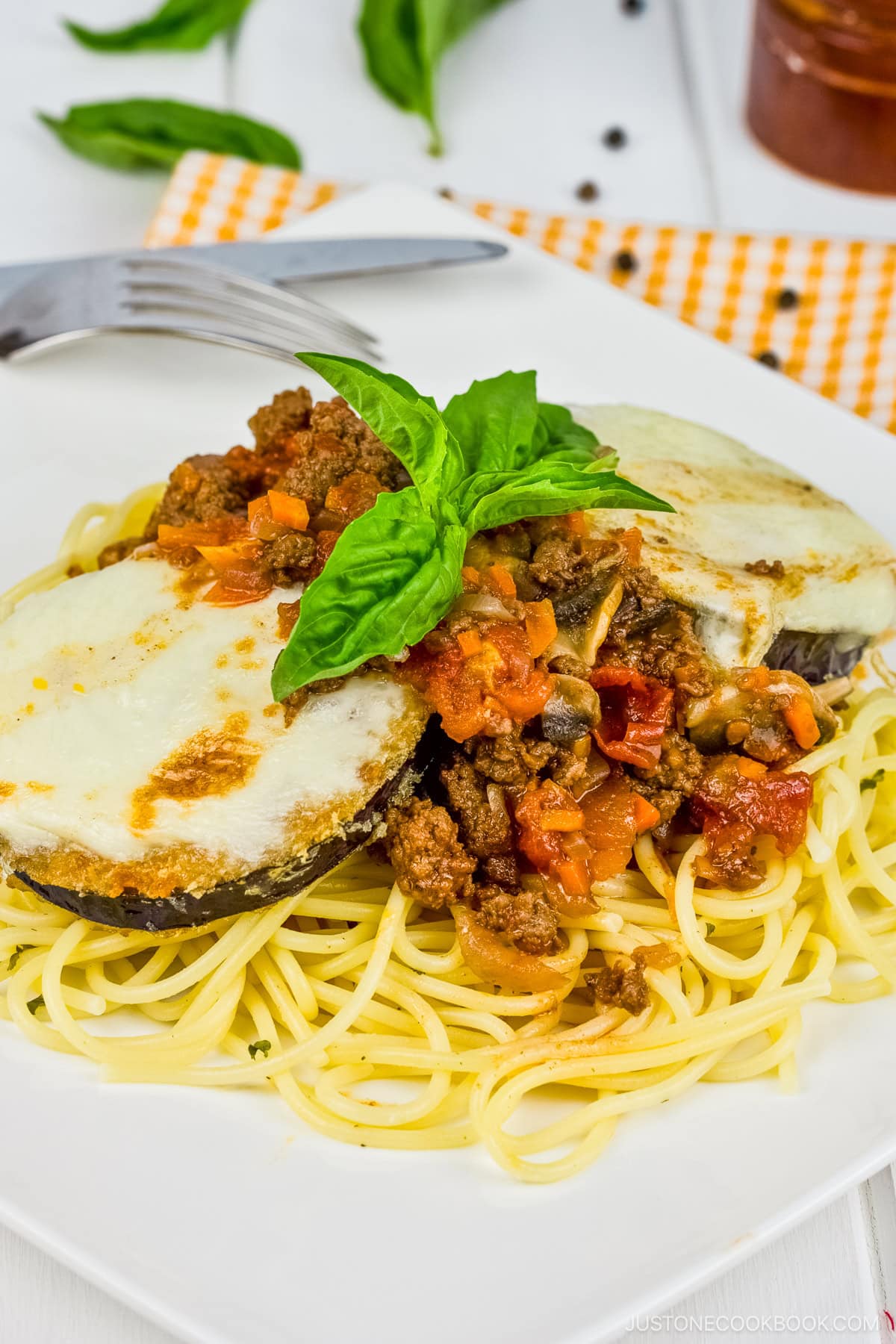 A white plate containing Eggplant Parmesan Spaghetti.