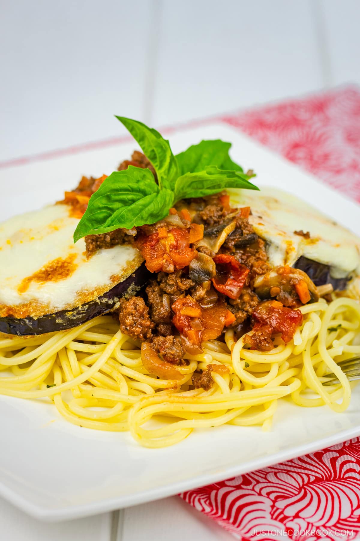 A white plate containing Eggplant Parmesan Spaghetti.