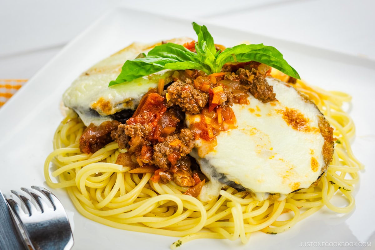 A white plate containing Eggplant Parmesan Spaghetti.