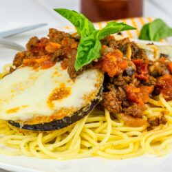 A white plate containing Eggplant Parmesan Spaghetti.
