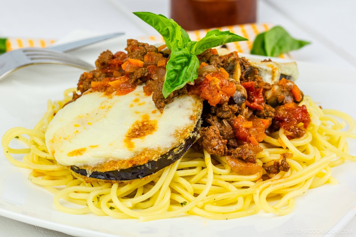 A white plate containing Eggplant Parmesan Spaghetti.