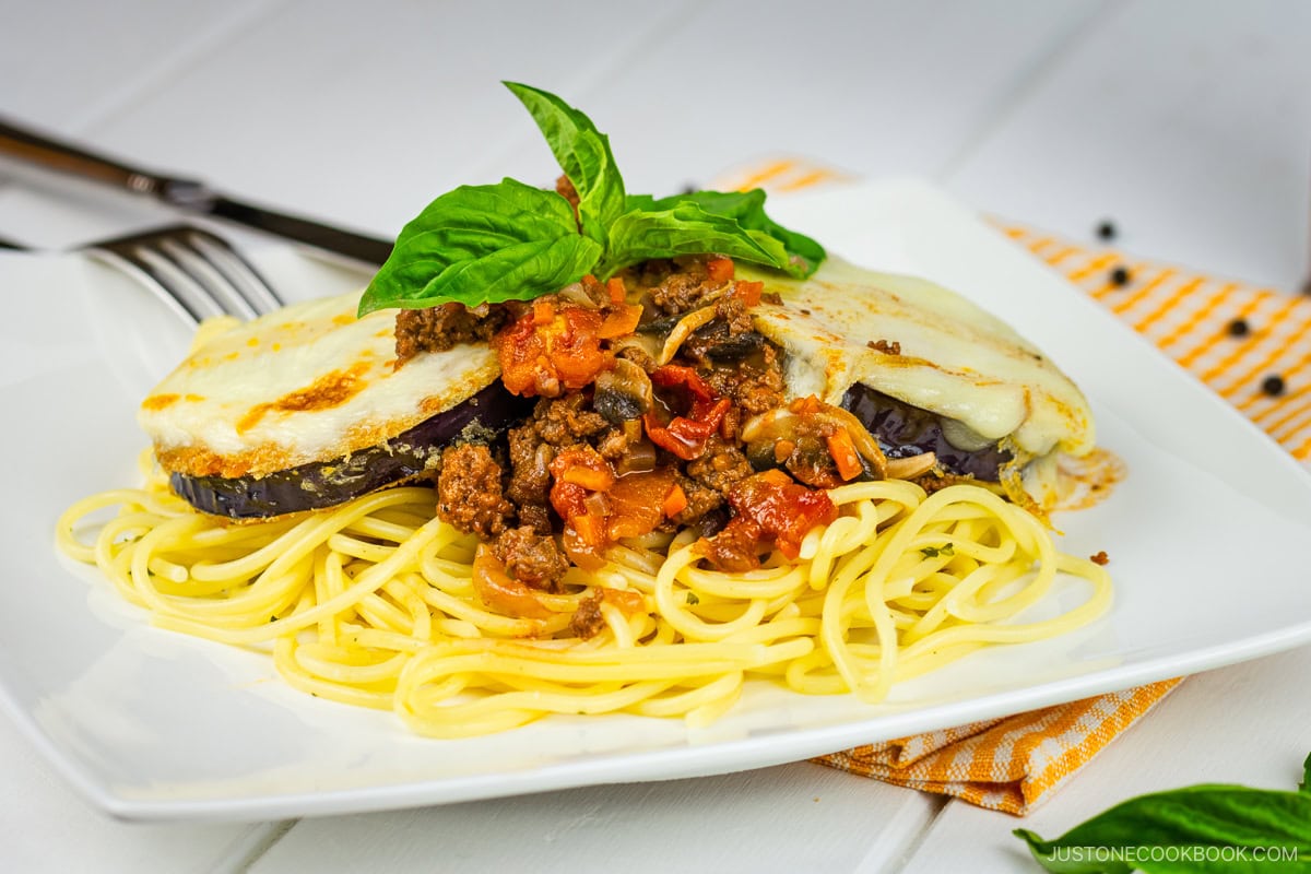 A white plate containing Eggplant Parmesan Spaghetti.
