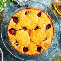 A whole plum cake on the glass cake stand.