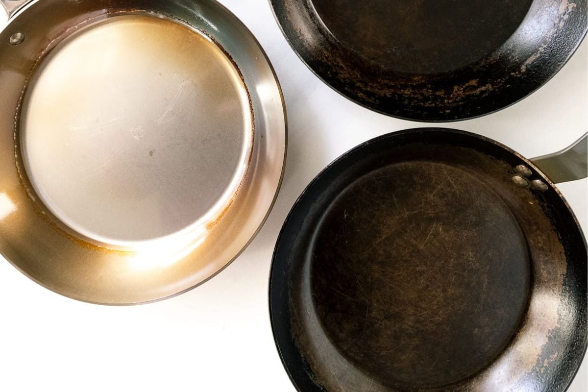 Used frying pans with baked-on grease and stuck-on food, showing wear from frequent use in a kitchen.