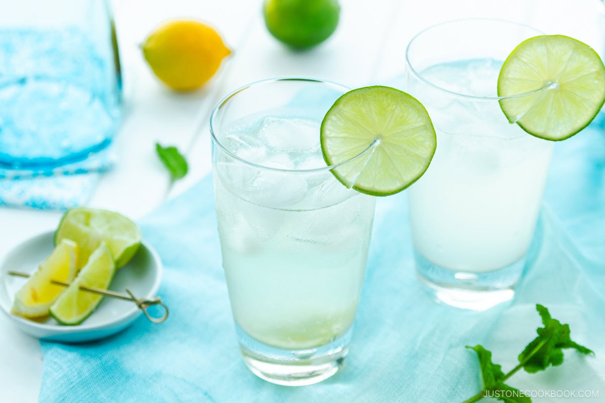 A glass filled with Japanese Yuzu Cocktail (Yuzu Chuhai) garnished with a slice of lime.