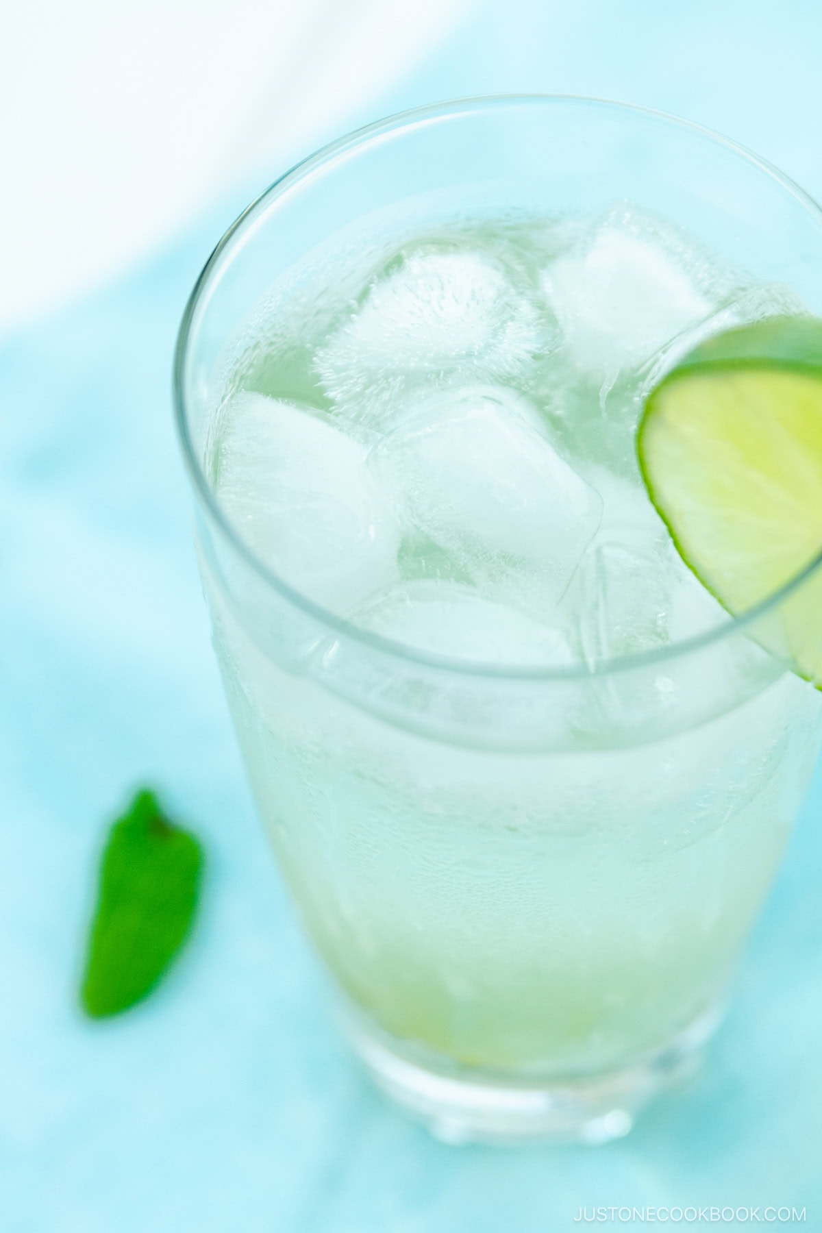 A glass filled with Japanese Yuzu Cocktail (Yuzu Chuhai) garnished with a slice of lime.